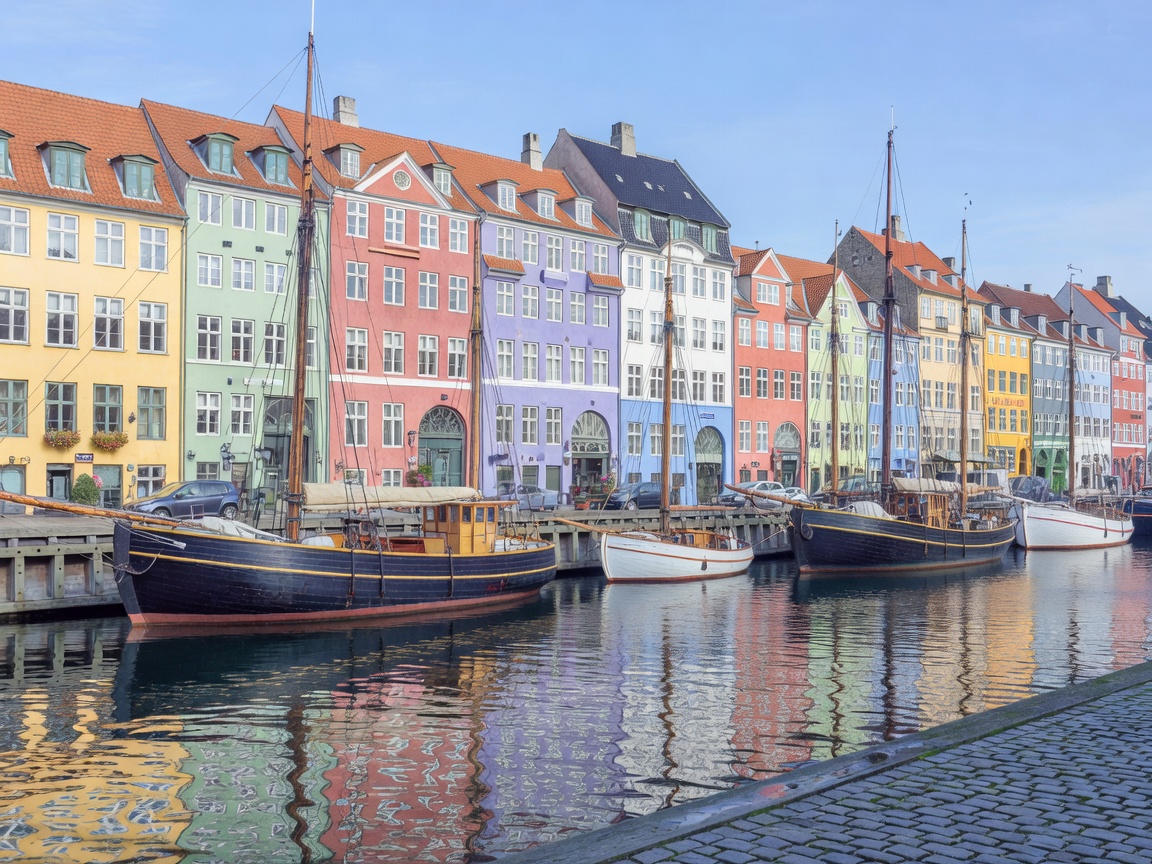 Vibrant pastel townhouse facades along Nyhavn canal side with historic wooden ships